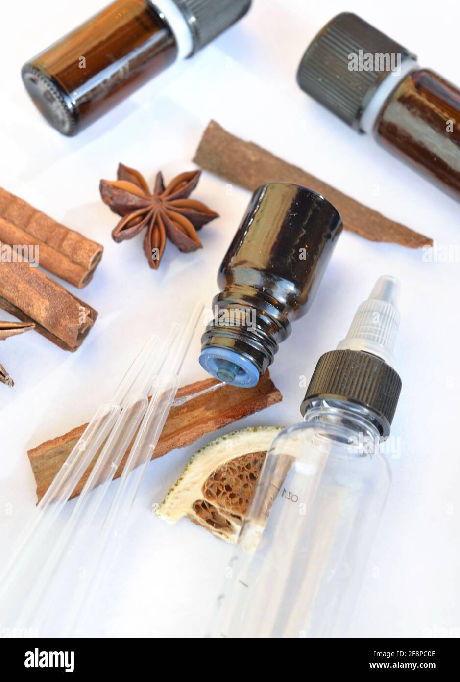 bouteille d'huile essentielle et de cannelle et d'anis sur un fond blanc avec pipette pour extraire l'essence Banque D'Images