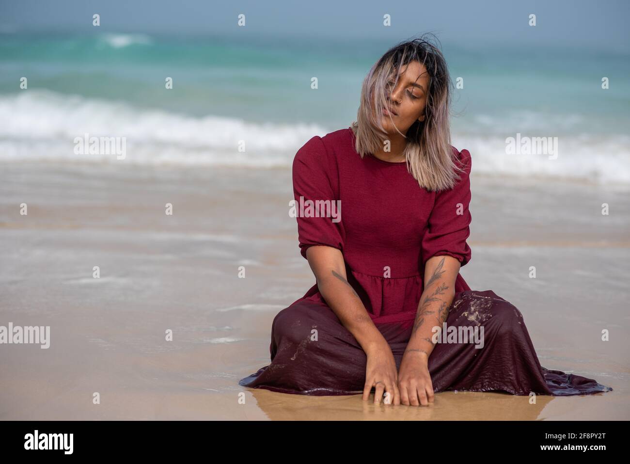 Femme assise sur la rive avec des vagues vues en arrière-plan Banque D'Images