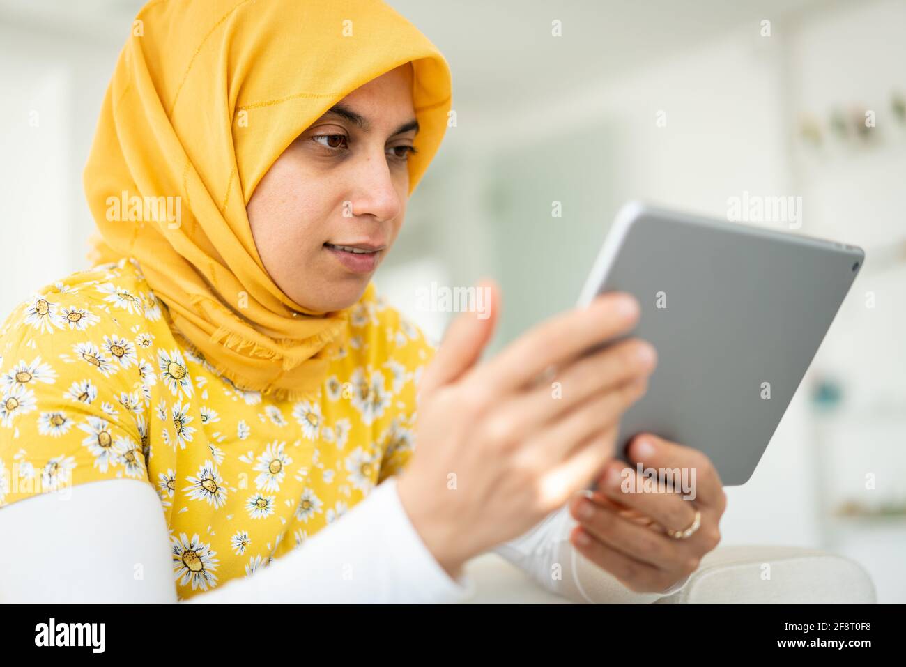 Femme musulmane travaillant sur une tablette chez elle Banque D'Images