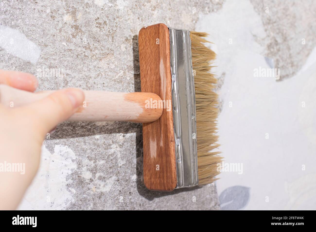 Le réparateur pare le vieux papier peint avec de l'eau à l'aide d'une brosse - une méthode de retrait de l'ancien papier peint du mur Banque D'Images