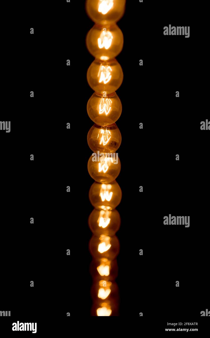 De nombreuses ampoules éclairant une lumière vive dans les lignes sombres. De nombreuses ampoules brûlent le plafond bas en haut. OldSchool technologie électrique ampoule verticale. JE Banque D'Images