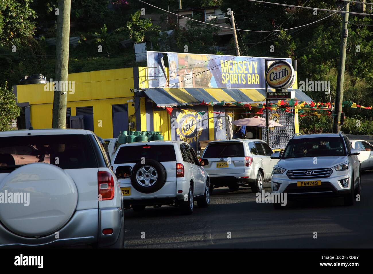 Grenada Road vers St George's Traffic à l'extérieur du bar sportif Mersevy Avec enseigne carib Beer Banque D'Images