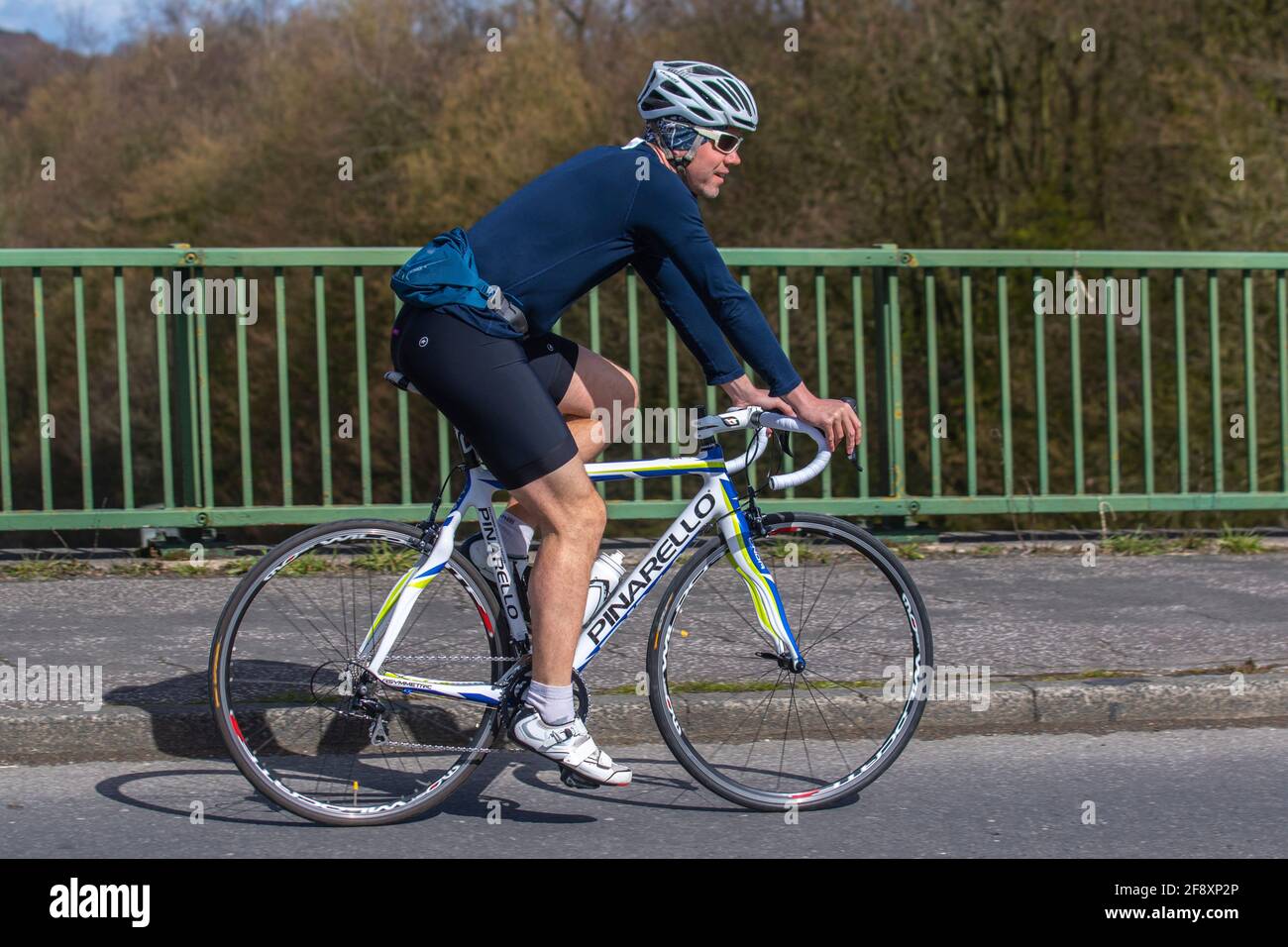 Cycliste mâle à cheval Pinarello vélo sur route sportive asymétrique sur la route de campagne traversant le pont d'autoroute dans la campagne du Lancashire, Royaume-Uni Banque D'Images