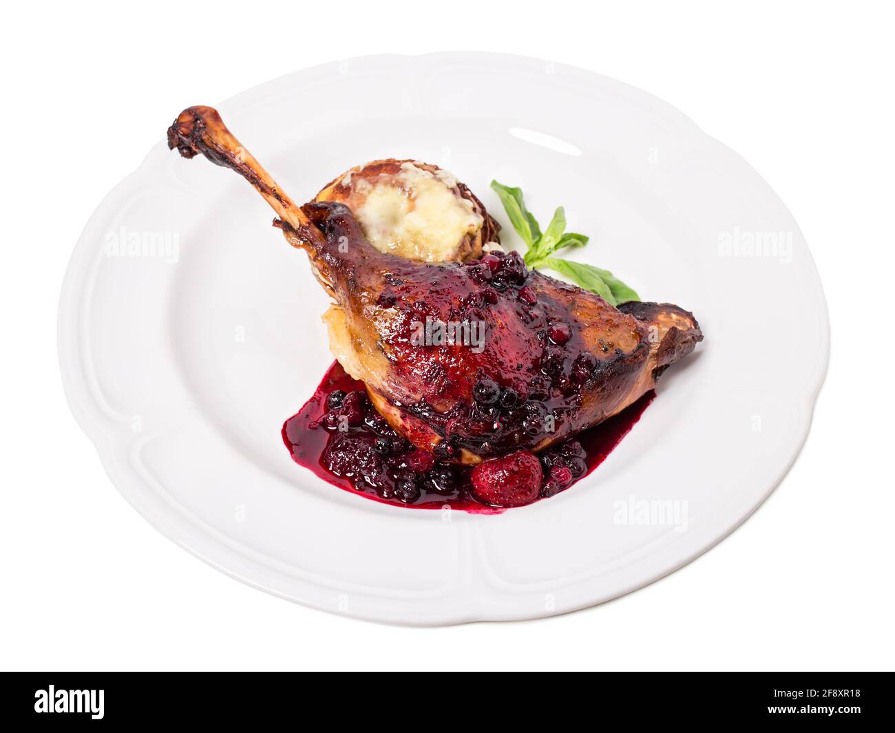 Délicieux confit de canard avec une sauce aux baies rouges et des tranches de pomme cuites recouvertes de fromage. Isolé sur un fond blanc. Banque D'Images