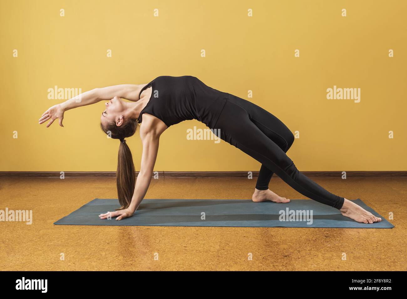 Une Femme En Tenue De Sport Noire Pratiquant Le Yoga Effectue Un