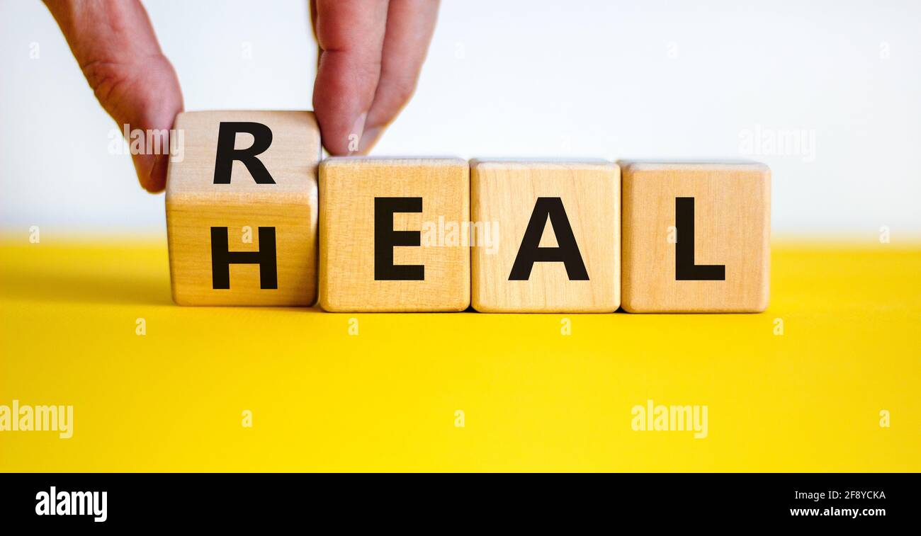 Symbole de correction réelle. Le docteur tourne un cube en bois avec les  mots 'Real HEAL'. Belle table jaune, fond blanc, espace de copie. Conce  médical et véritable guérir Photo Stock -