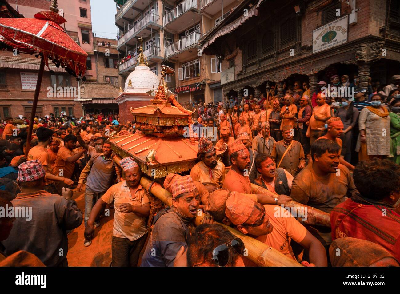 Bhaktapur, Népal. 15 avril 2021. Les dévotés couverts de vermilion en poudre portent un char lorsqu'ils encerclent le Temple Balkumari pendant le festival de poudre couvert de Jatra vermilion. Les fêtards transportaient des chars des dieux et des déesses hindous et se précipitèrent sur des vermillions de poudre les uns sur les autres dans le cadre des célébrations du nouvel an népalais. Crédit : SOPA Images Limited/Alamy Live News Banque D'Images
