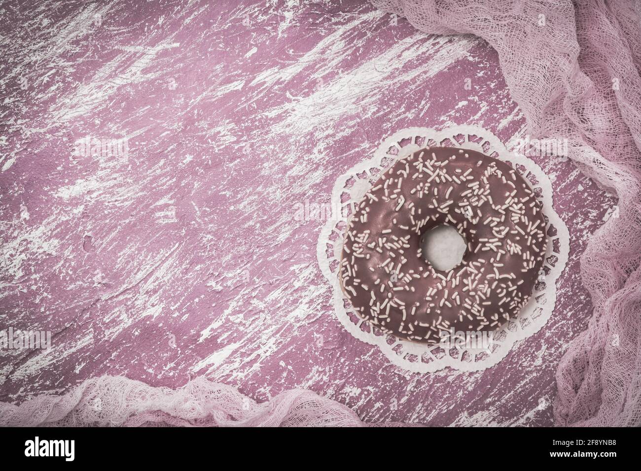 Donut glacé rose sur fond peint rose et blanc, couleur désaturée pour un look vintage monochrome, vue du dessus avec espace pour les copies Banque D'Images