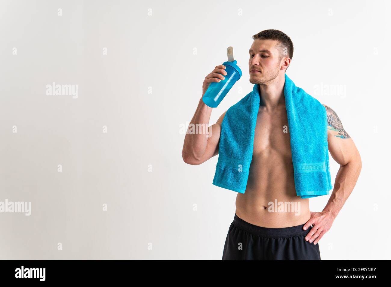 Homme boire-eau fitness est pompé avec une serviette sur un fond blanc isolé fitness athlète style de vie, entraînement homme gars, serviette alimentation parfaite, Banque D'Images