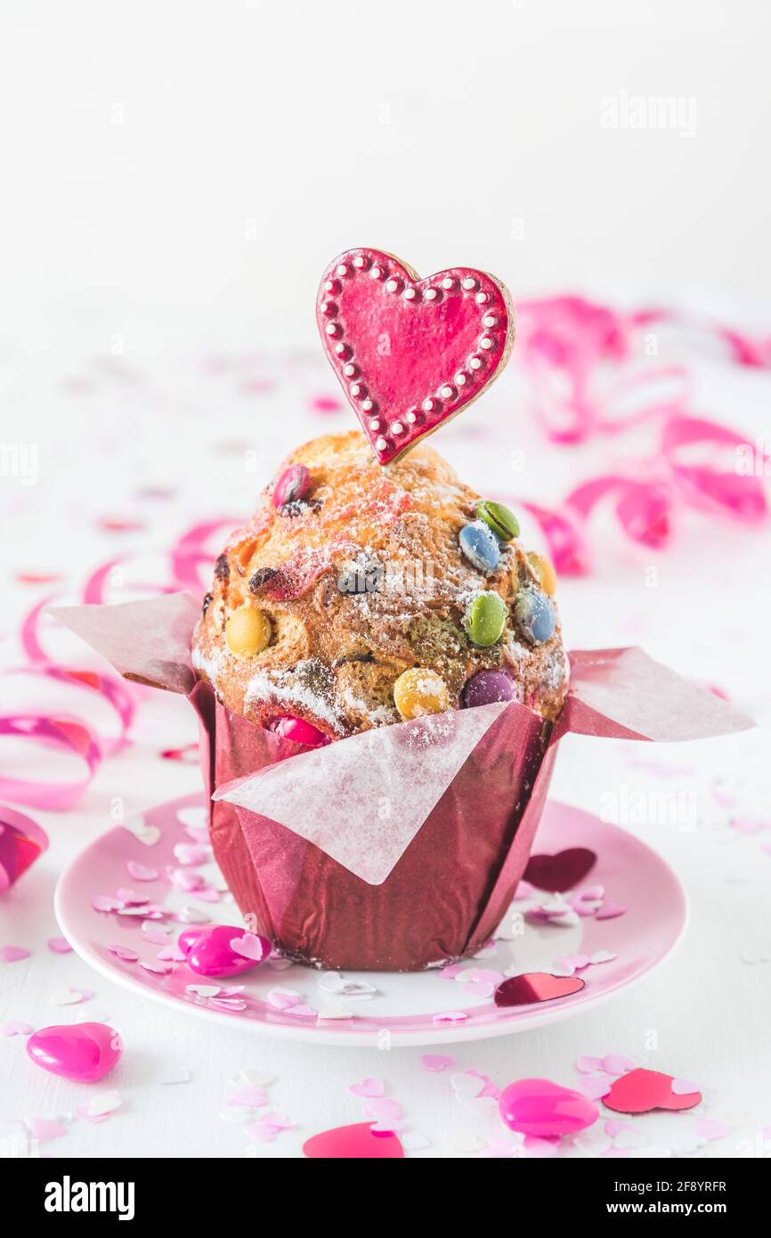 Muffin aux grains de chocolat, décoré de coeurs rouges, roses et blancs pour les anniversaires ou les Saint-Valentin, fond blanc, vertical avec espace pour les copies Banque D'Images