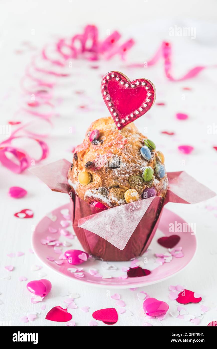 Muffin aux grains de chocolat, décoré de coeurs rouges, roses et blancs pour les anniversaires ou les jours de la Saint-Valentin, fond blanc, vertical Banque D'Images