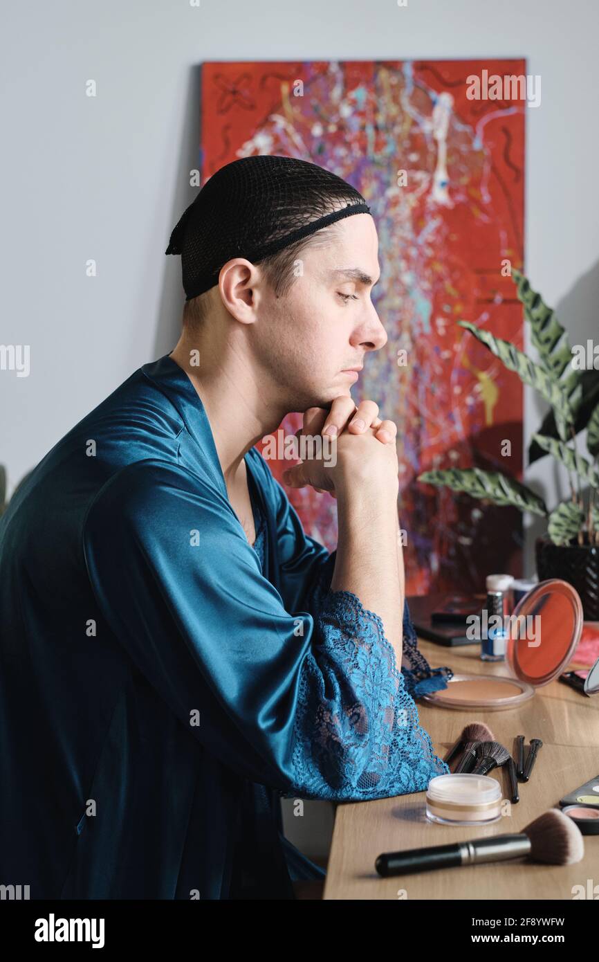 Jeune homme assis à la table avec des cosmétiques et de la préparation pour sa performance Banque D'Images