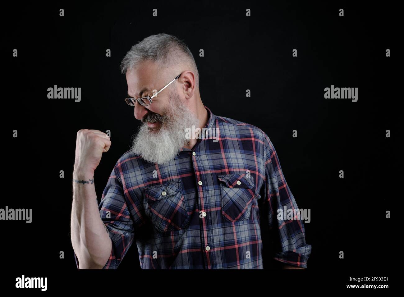 Portrait d'un homme européen mûr, joyeux et émotif, qui élève les poings et hurle, triomphant ou applaudisse tout en regardant un match de football Banque D'Images