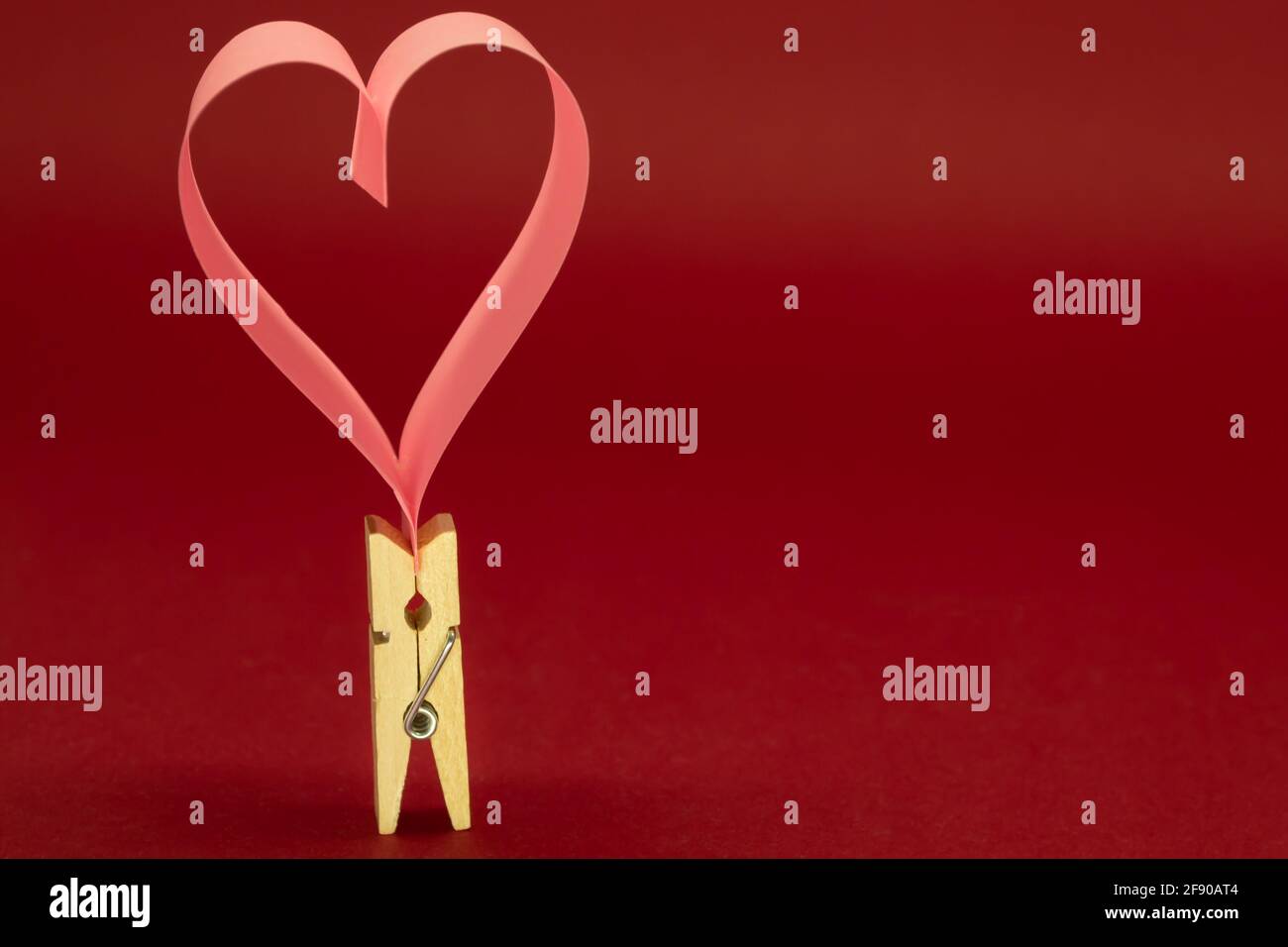 Le concept de l'amour. Épinglette en bois avec coeur en papier sur fond rouge Banque D'Images
