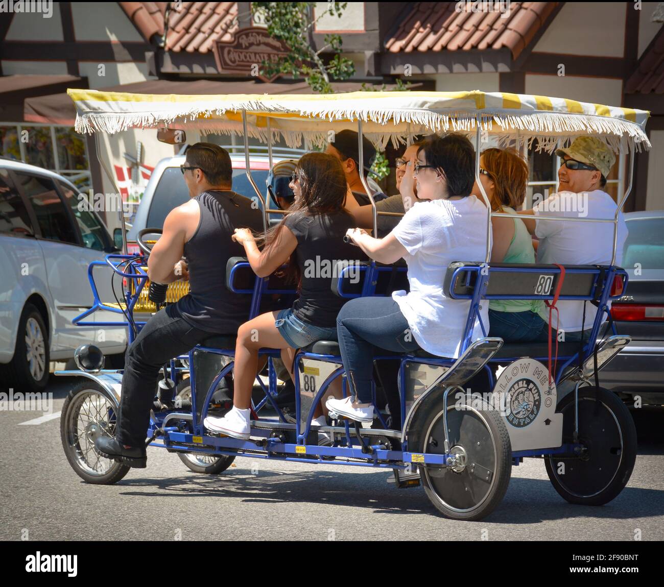 Vue arrière latérale de huit personnes pédalant un vélo à 4 roues pour le plaisir et le tourisme de loisirs dans le village danois de Solvang, CA, Etats-Unis Banque D'Images