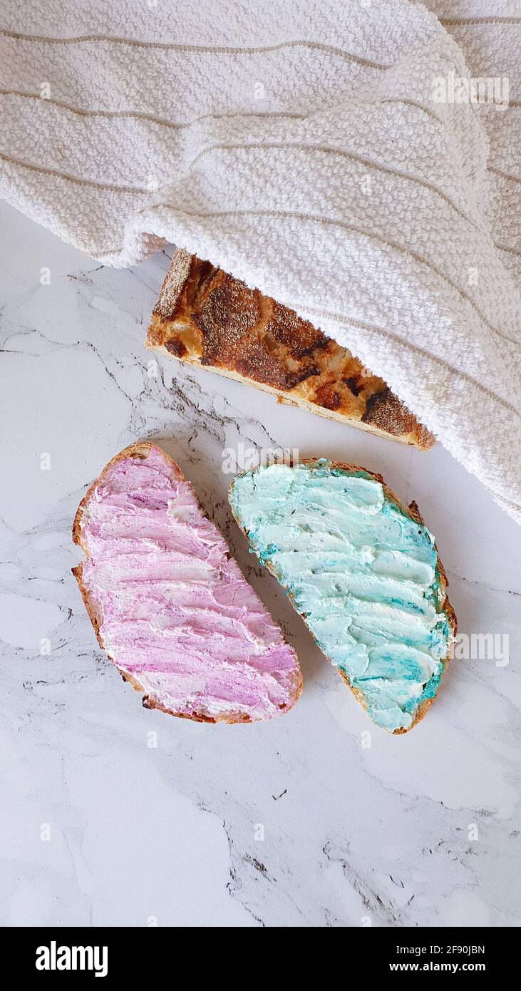 Deux morceaux de pain au fromage à la crème rose et cyan et un pain Banque D'Images