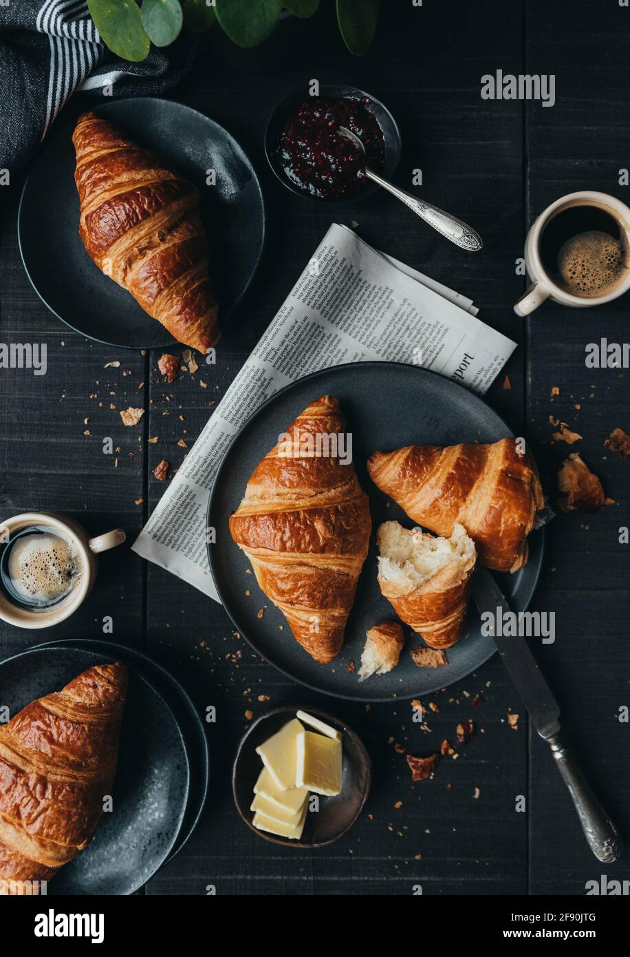 Assiettes de croissants avec café et confiture sur table noire. Banque D'Images Assiettes de croissants avec café et confiture sur table noire. Banque D'Images