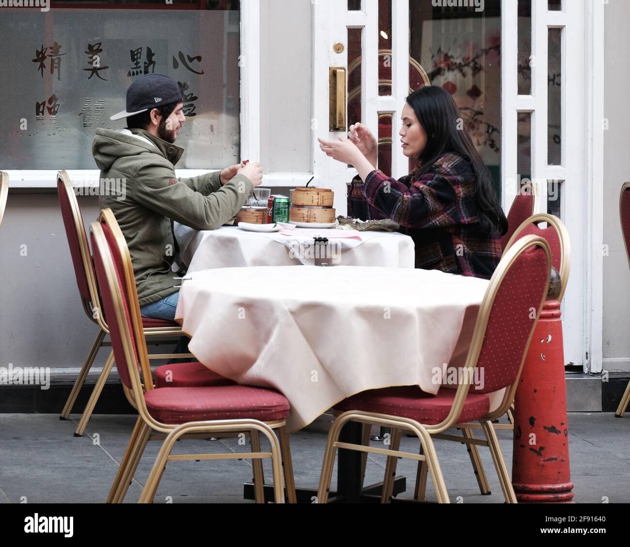 Deux convives assis sur une table sur le trottoir apprécient dimsum dans le quartier chinois de Londres, tandis que les restrictions du coronavirus se soulagées et que l'hospitalité en plein air revient en Angleterre. Banque D'Images