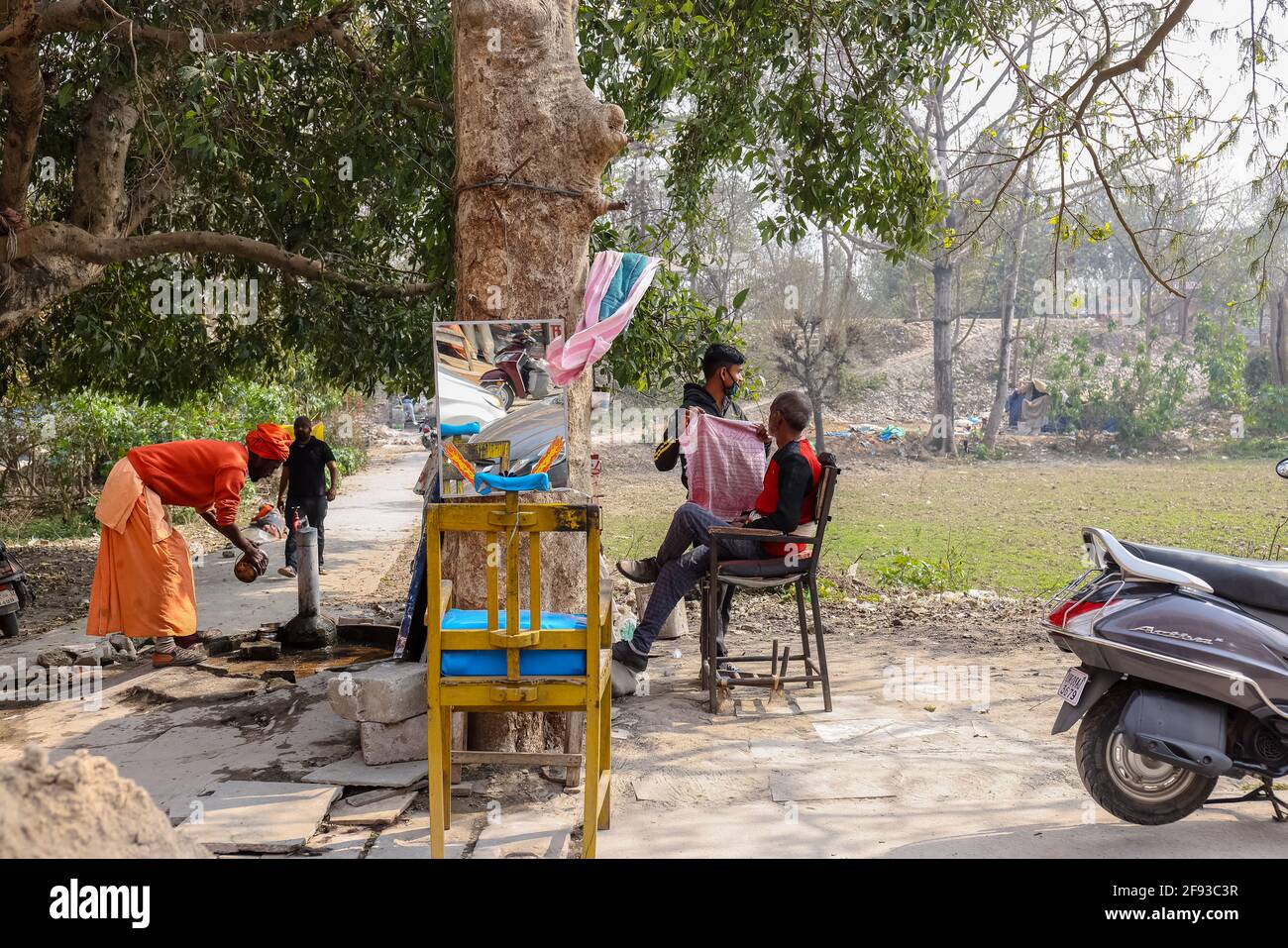 HARIDWAR, UTTARAKHAND, INDE - FÉVRIER 2021 : un barbier non identifié dans la rue de Haridwar près de Har ki pauri Ghat raser le client. Banque D'Images