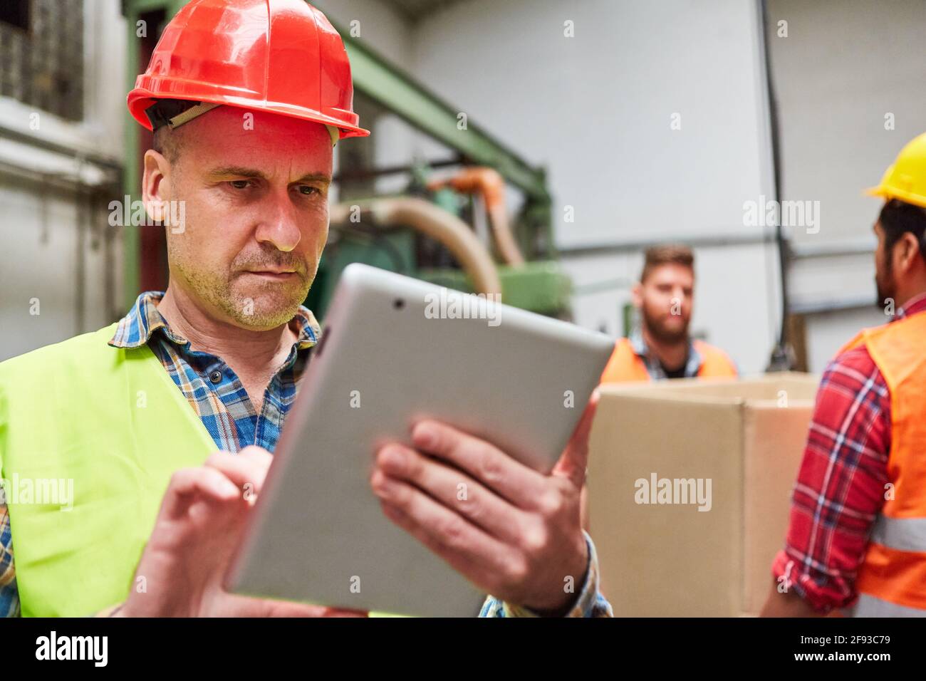 Le préparateur de commande avec une tablette vérifie les marchandises entrantes ou la commande en usine Banque D'Images