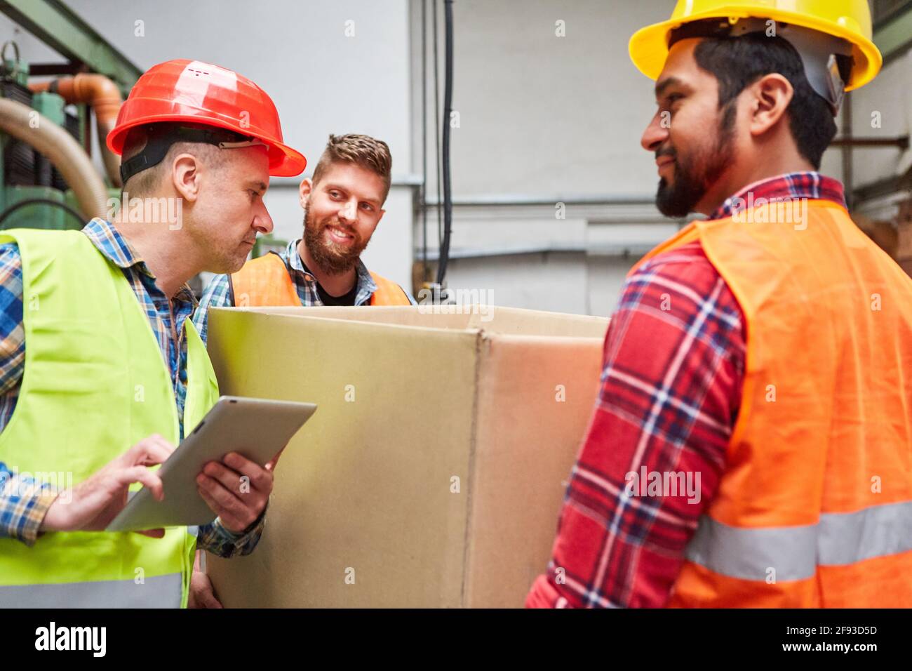 Le préparateur de commande avec l'ordinateur tablette vérifie les boîtes en carton au niveau du service des marchandises entrantes de l'usine Banque D'Images
