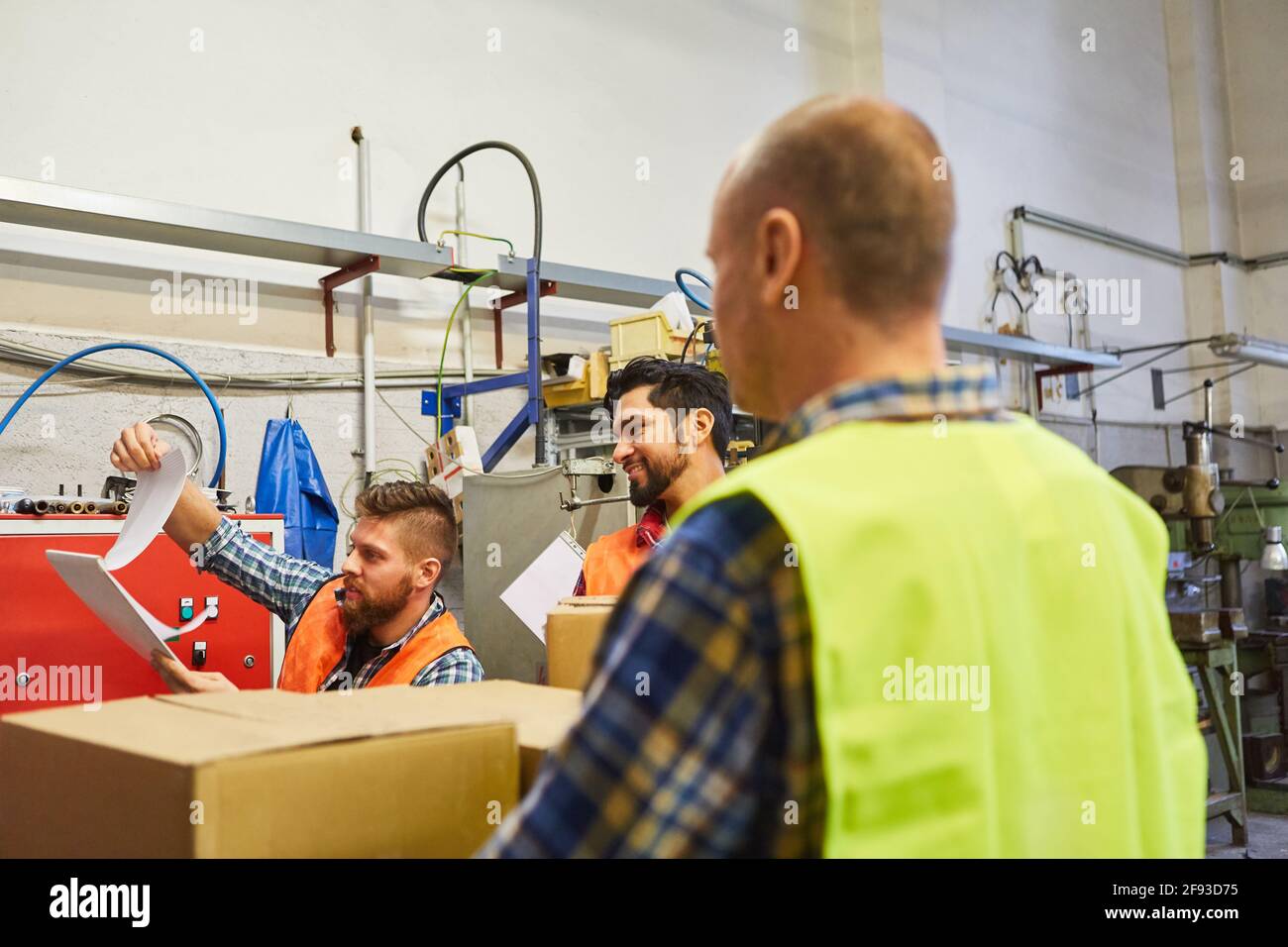 L'employé de l'entrepôt et ses collègues utilisent une liste de contrôle pour vérifier la commande ou la livraison Banque D'Images