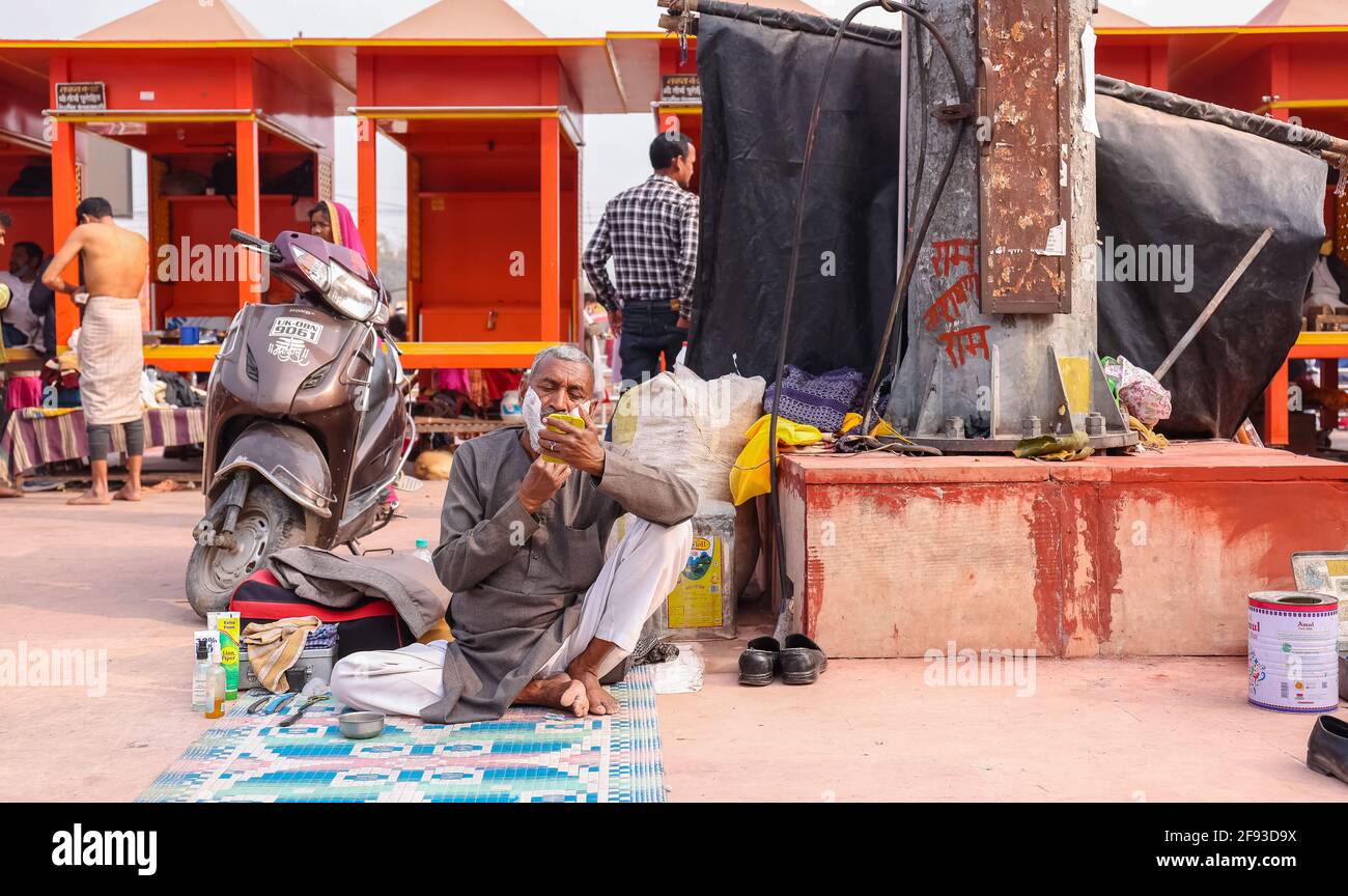 HARIDWAR, UTTARAKHAND, INDE - FÉVRIER 2021 : un barbier non identifié dans la rue de Haridwar près de Har ki pauri Ghat raser le client. Banque D'Images