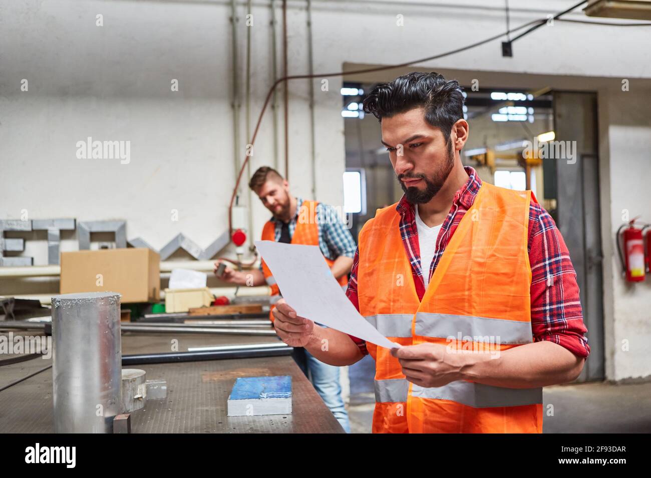 Un employé qualifié comme employé d'entrepôt et préparateur de commande lit un ordre dans l'atelier dans la société Banque D'Images