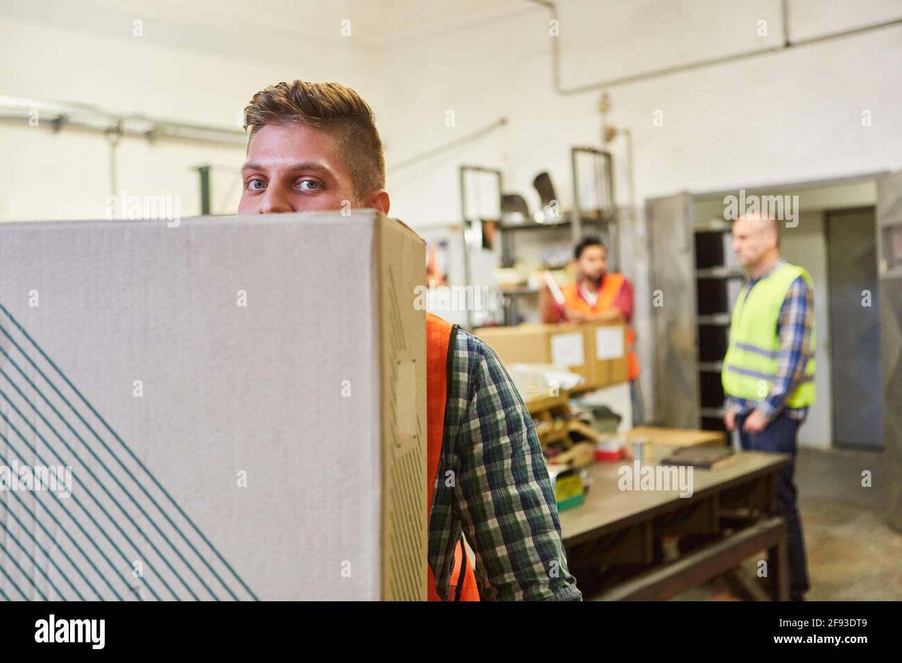 L'employé d'entrepôt transporte un package pour une commande dans le direction de l'entrepôt Banque D'Images