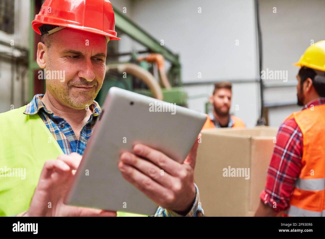 Un employé d'entrepôt spécialisé vérifie une livraison sur le Tablet PC dans la société d'expédition ou dans l'usine de métal Banque D'Images
