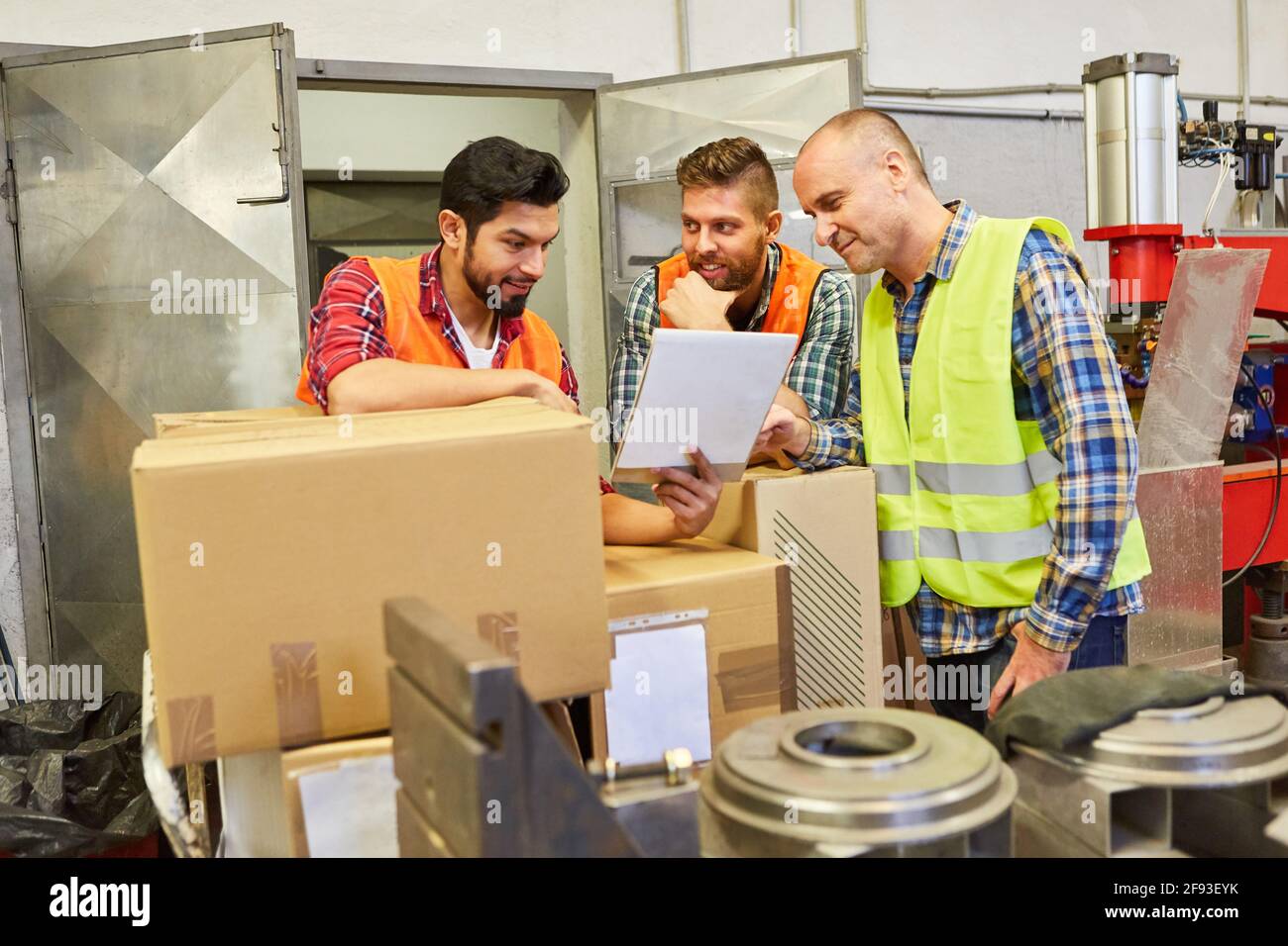 Le groupe d'employés de l'entrepôt qui ont des boîtes en carton discute de la commande du client dans l'entrepôt d'expédition d'une usine Banque D'Images