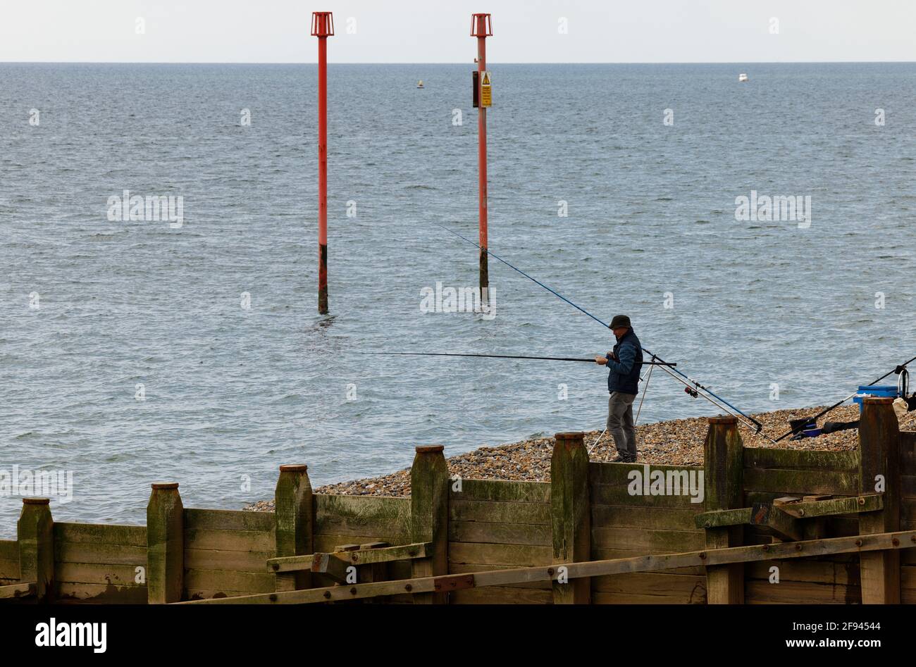 Un homme pêchant depuis une plage sur la côte sud de l'Angleterre. Banque D'Images