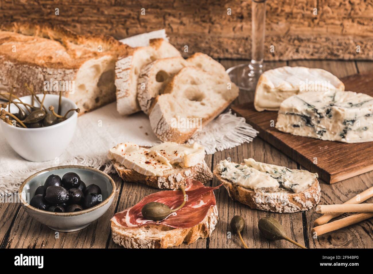 Pain blanc croustillant avec bacon et fromage et un bol avec olives sur table rustique en bois Banque D'Images