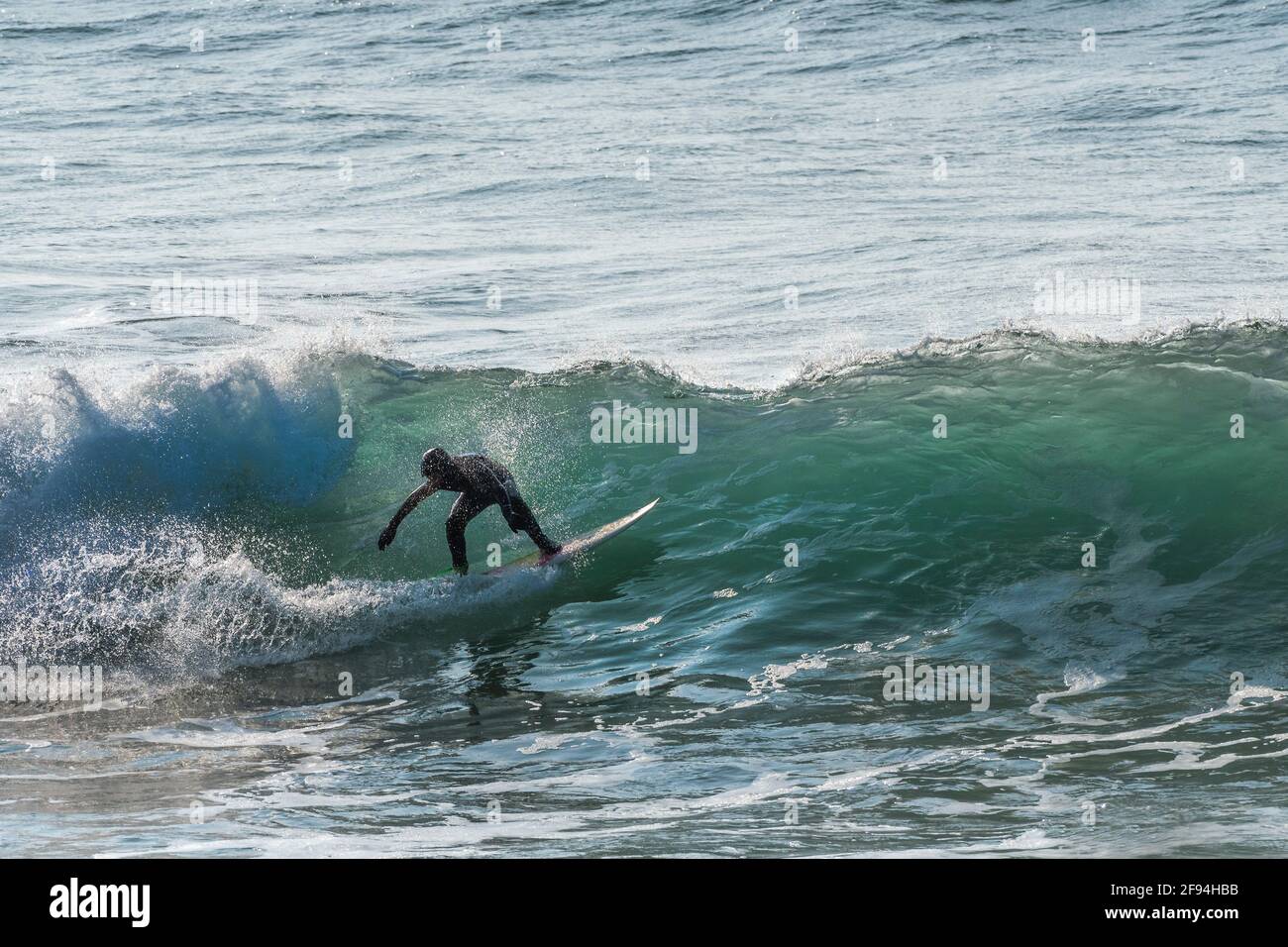 Un surfeur à cheval sur une vague dans la baie de Fistral à Newquay en Cornwall. Banque D'Images
