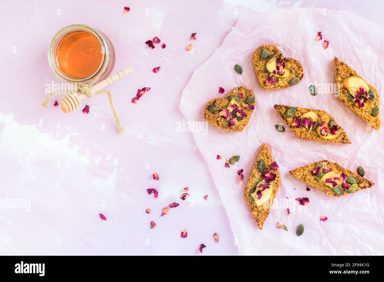 Barres de muesli aux pommes faites maison, décorées de graines de pomme et de citrouille séchées, sur fond rose pâle, vue du dessus Banque D'Images