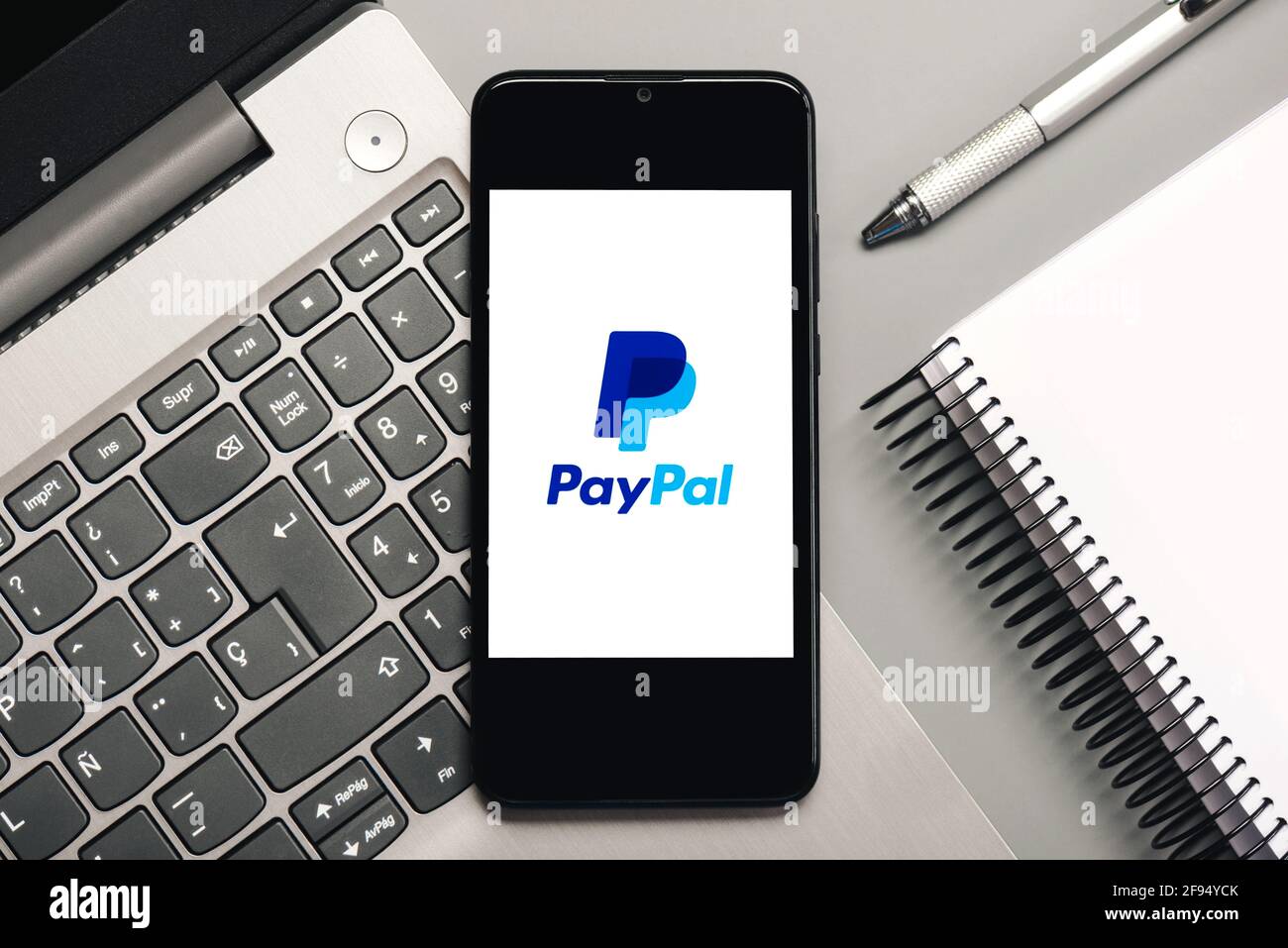 Logo PayPal sur écran noir du smartphone avec ordinateur portable et bloc-notes sur fond gris Banque D'Images