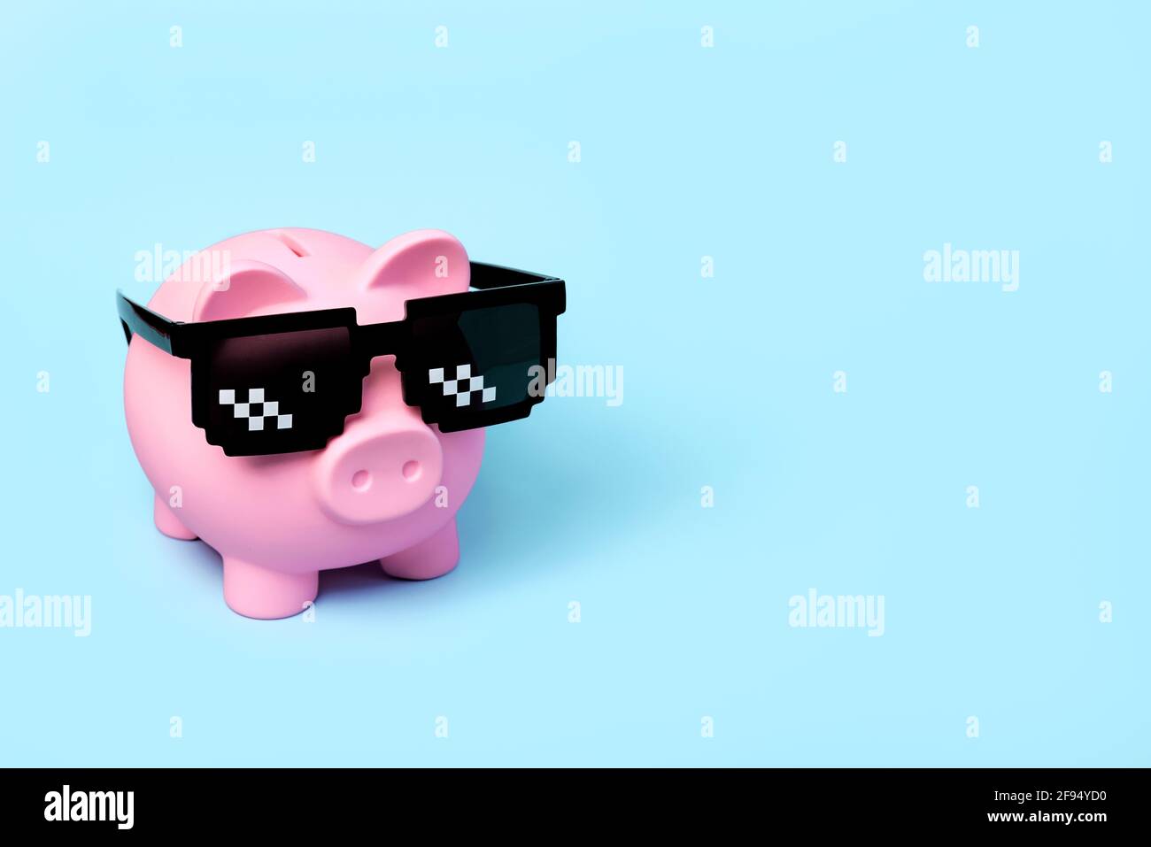 Banque d'argent de porc rose avec des lunettes de soleil noires sur un bleu arrière-plan Banque D'Images