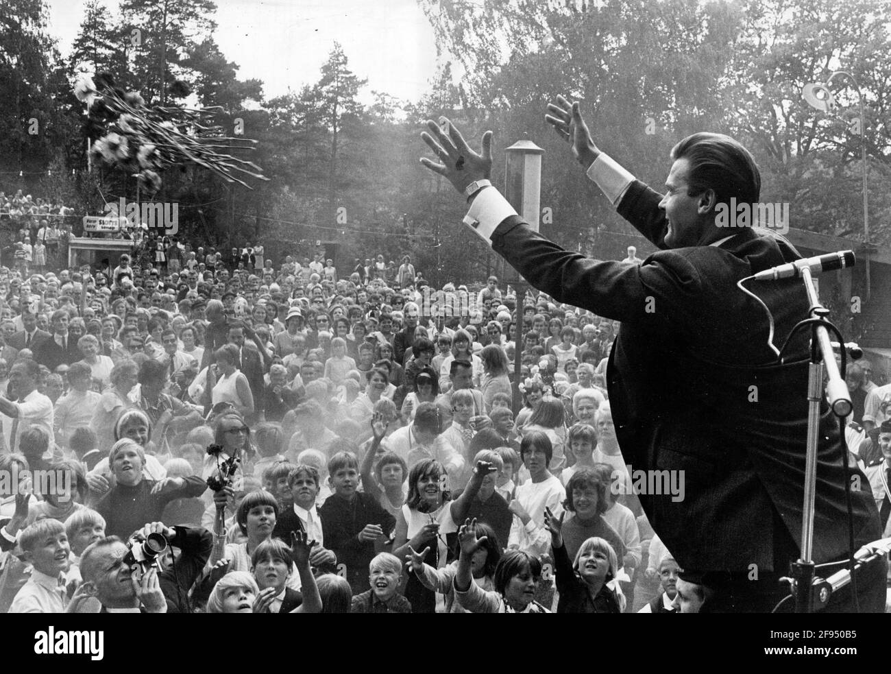 Acteur Roger Moore célébrant le milieu de l'été dans le Folkpark de Gustavsberg, à l'extérieur de Stockholm, en Suède, le 25 juin 1966. Roger Moore a remis 100 œillets aux dames du public. Photo: Ake Malmstrom / DN / TT / code 37 Banque D'Images