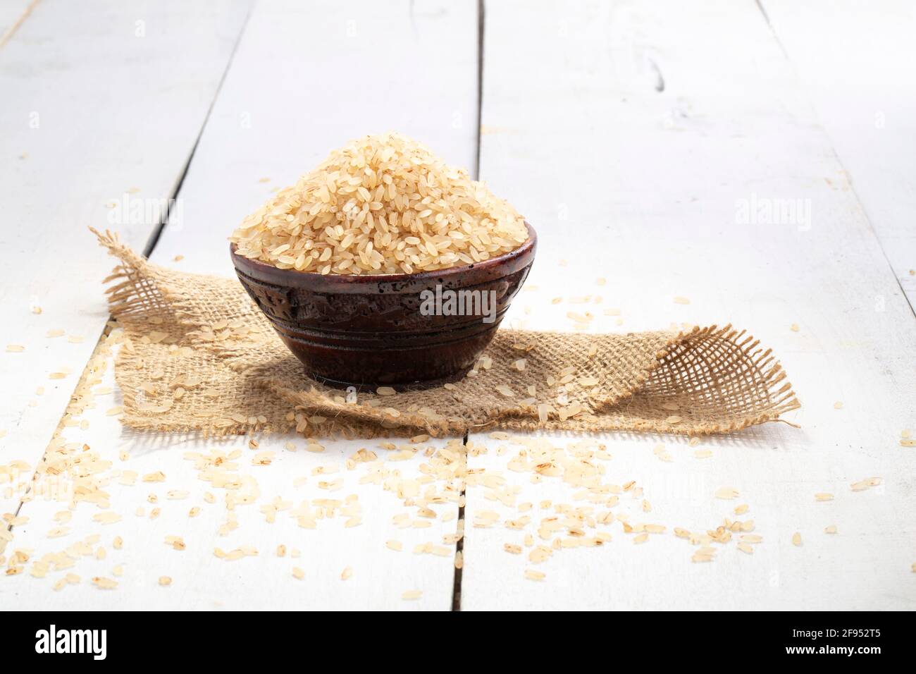 Riz Kerala Matta  riz étuvé ou palakadan matta ou rouge riz disposé dans un bol en bois sur lequel est placé un chiffon jute avec fond blanc Banque D'Images