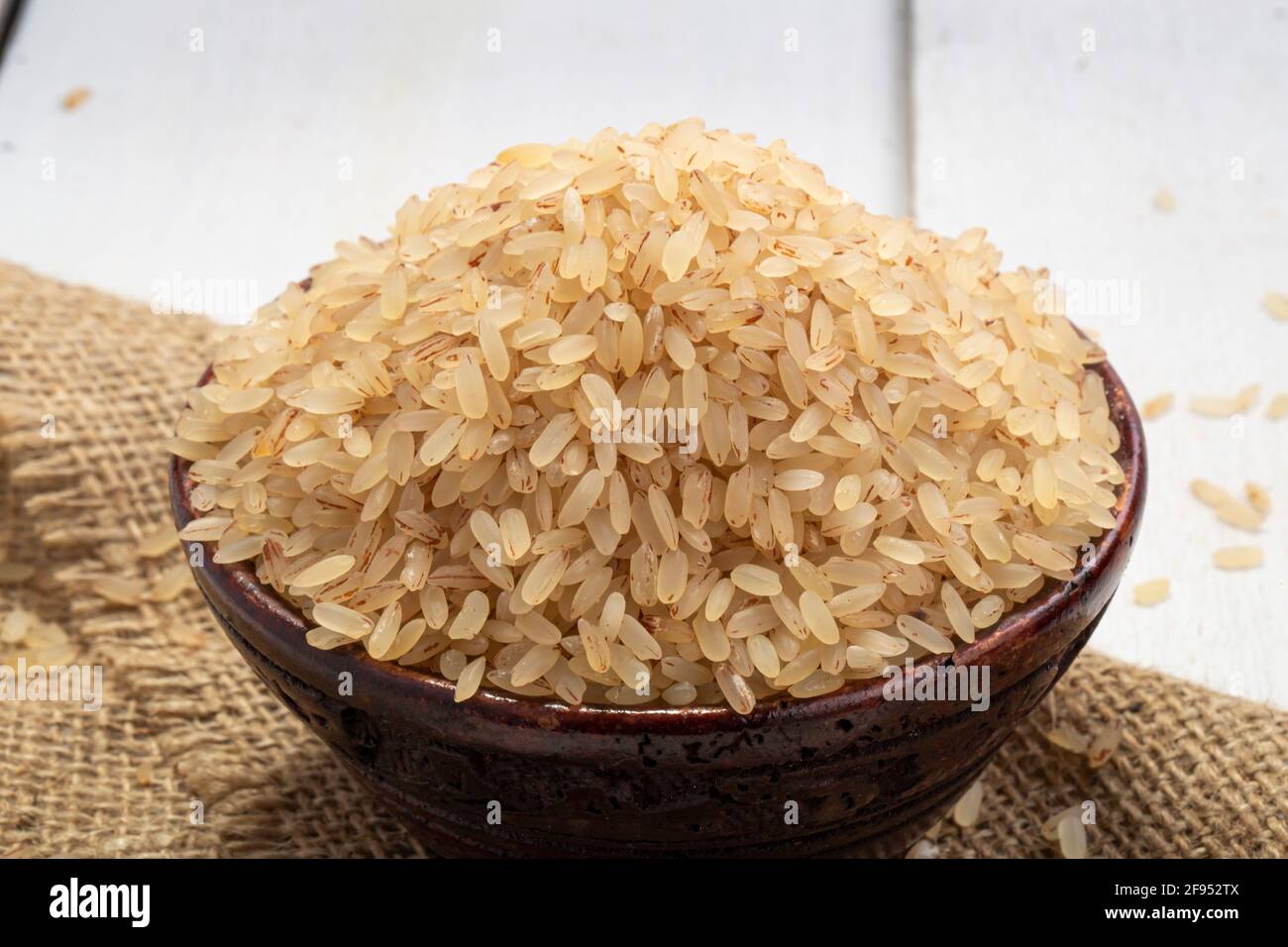 Riz Kerala Matta  riz étuvé ou palakadan matta ou rouge riz disposé dans un bol en bois sur lequel est placé un chiffon jute avec fond blanc Banque D'Images