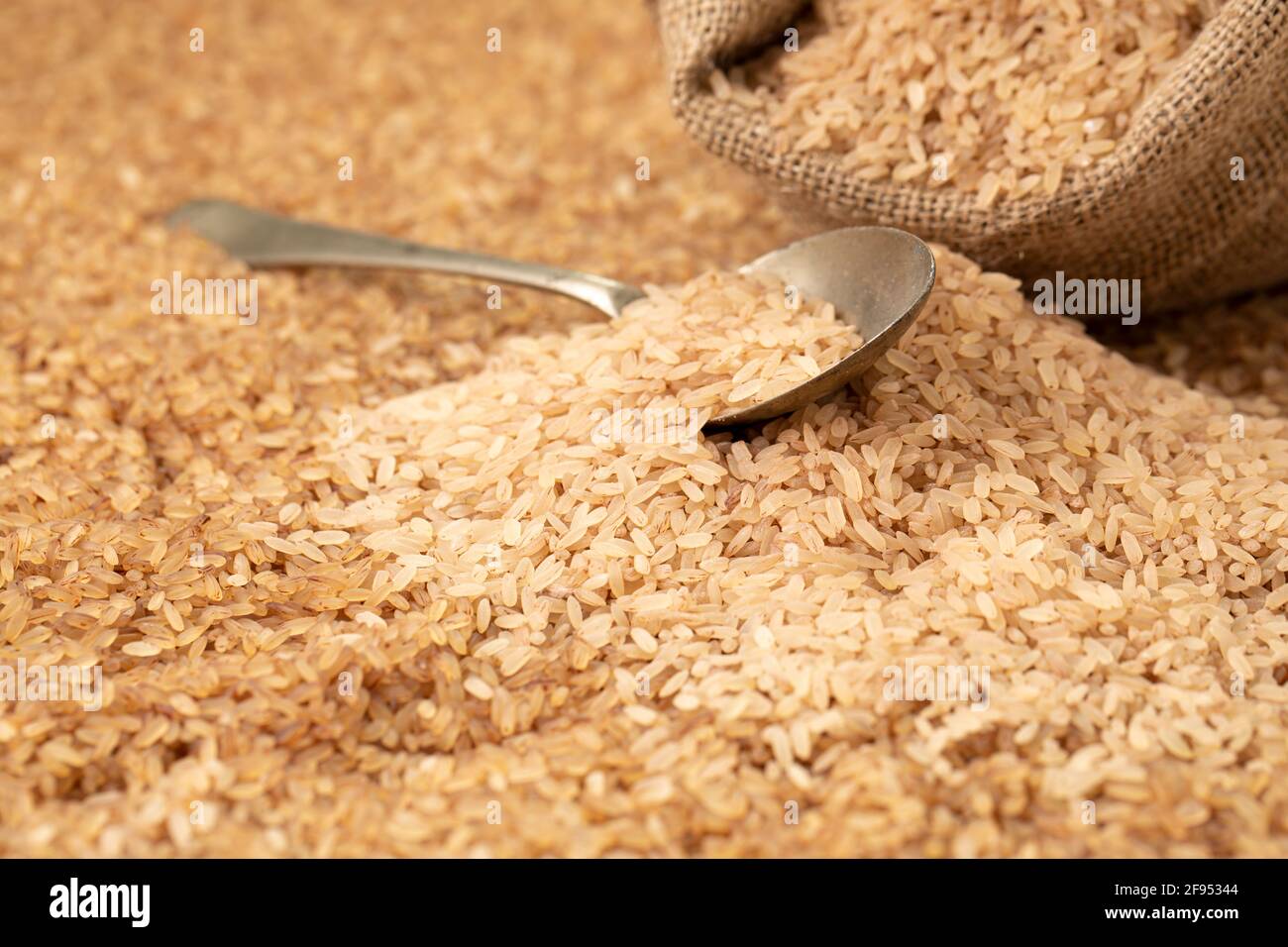 Riz Kerala Matta _riz étuvé ou palakadan riz matta disposé dans une cuillère et sac de burlap avec fond de riz rouge mutta, topview. Banque D'Images