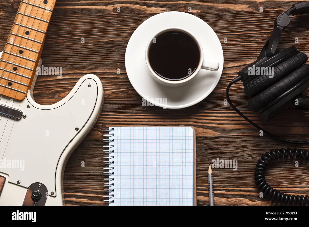 Une tasse de café, une guitare, un casque et un carnet sur une planche en bois sombre. Vue de dessus. Banque D'Images