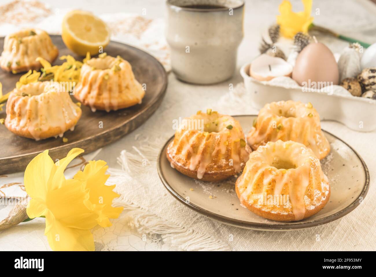 Petits gâteaux faits maison au citron (muffins) sur une assiette sur une table de pâques avec des fleurs de printemps fraîches. Banque D'Images