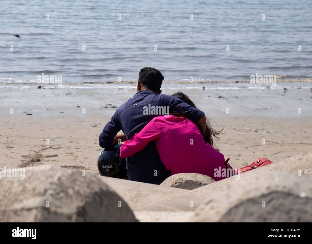 Jeune couple assis sur la plage de Mahim Bay à Mumbai, Maharashtra, Inde, Asie. Banque D'Images