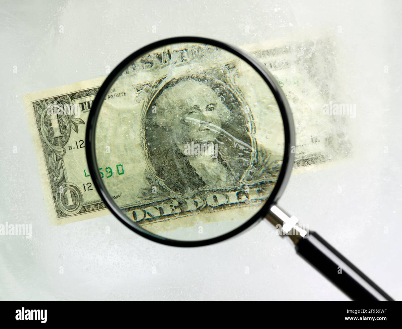 La facture du dollar américain est enchâssée dans la glace, vue par une loupe verre Banque D'Images