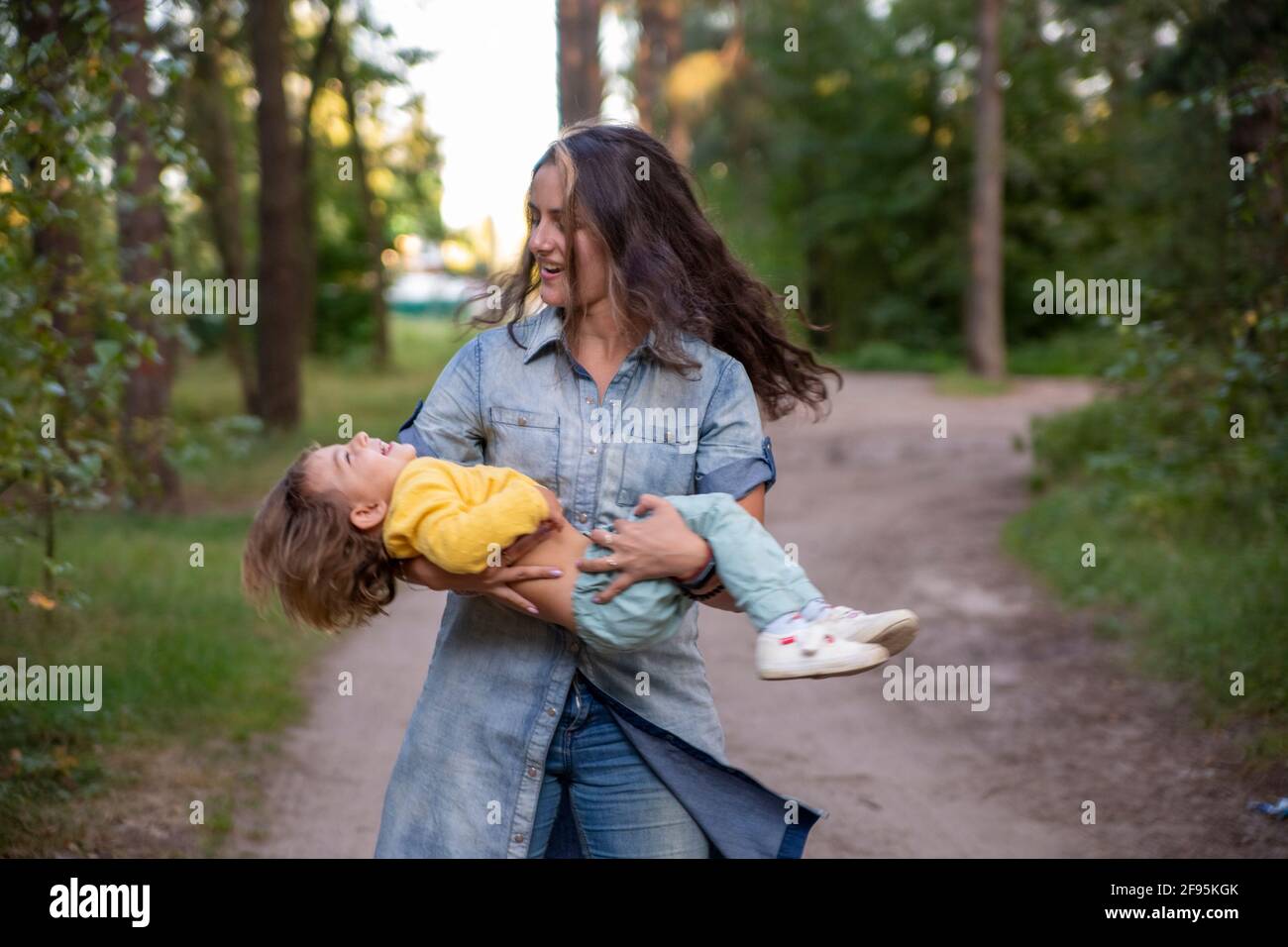La Jeune Mere Tourne Avec Un Bebe Dans Les Bras Bonne Maman Dansant Avec Un Tout Petit Sur Le Fond De La Nature Et De La Foret Maman Et Fille Rient Photo Stock