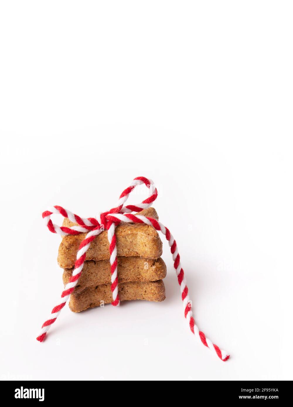Trois biscuits en forme d'os marron pour chiens noués avec du rouge et du ficelle blanche Banque D'Images