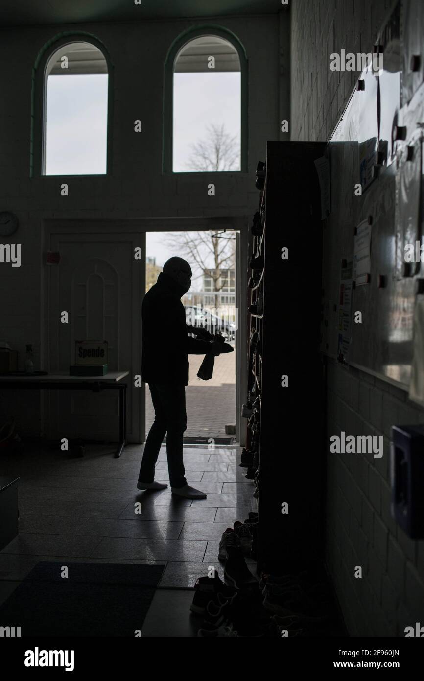 Hanovre, Allemagne. 16 avril 2021. Un homme prend ses chaussures avant la prière du premier vendredi à l'entrée de la mosquée 'Casjid El-Ummah' pendant la première semaine du Ramadan. Afin de pouvoir garder les distances lors de la prière, il y a deux prières du vendredi. Environ 250,000 à 300,000 musulmans vivent en Basse-Saxe. Le mois de jeûne du Ramadan a commencé cette année le 13 avril et se termine le 12 mai. Crédit : EMAN Helal/dpa/Alay Live News Banque D'Images