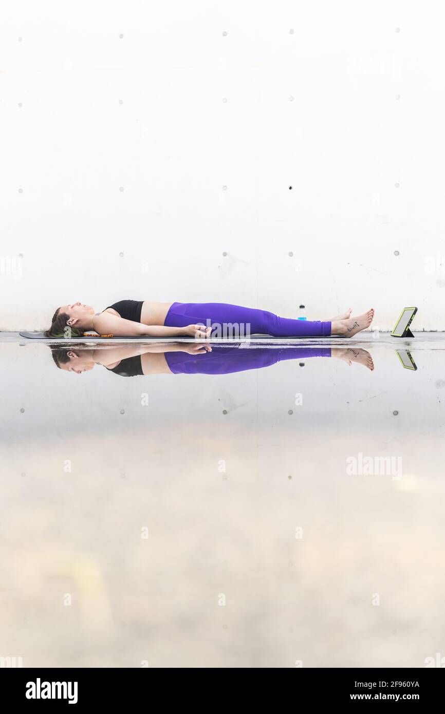 Athlète femme faisant la posture savasana pendant un yoga en ligne classe Banque D'Images