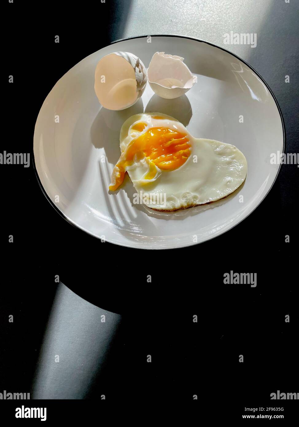 Œuf frit sous forme de coeur sur un plaque blanche avec coques Banque D'Images